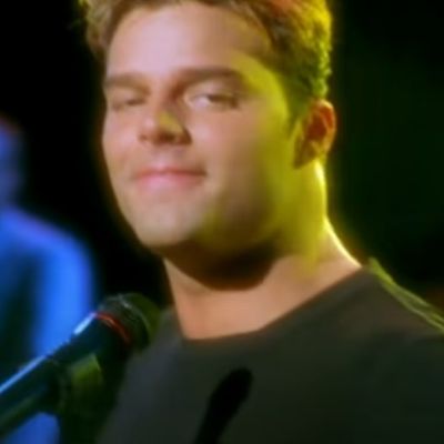 Ricky Martin is looking directly at the camera as he has a mic in front of him.